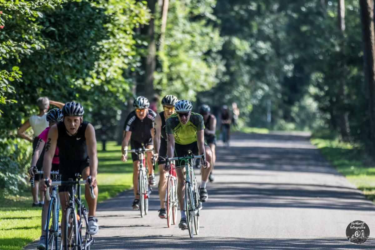 Een groep mensen fietst over een weg.