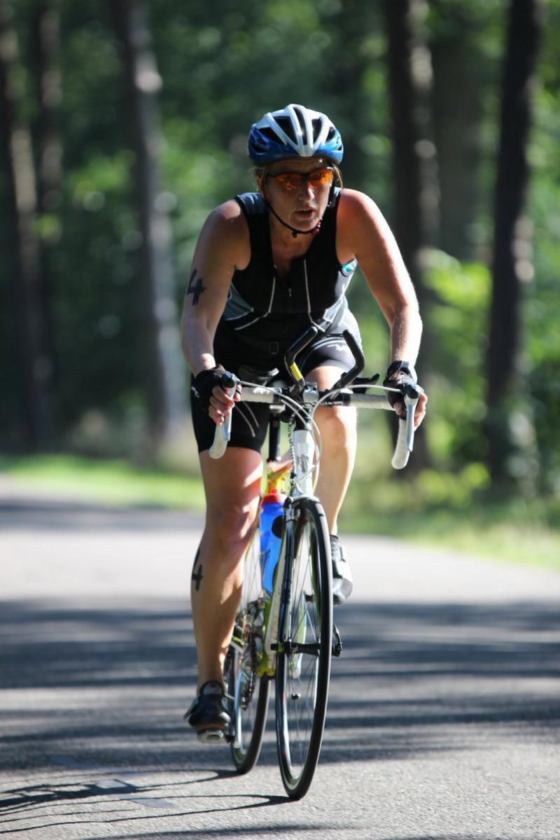 Een vrouw met een helm op fietst op de weg.