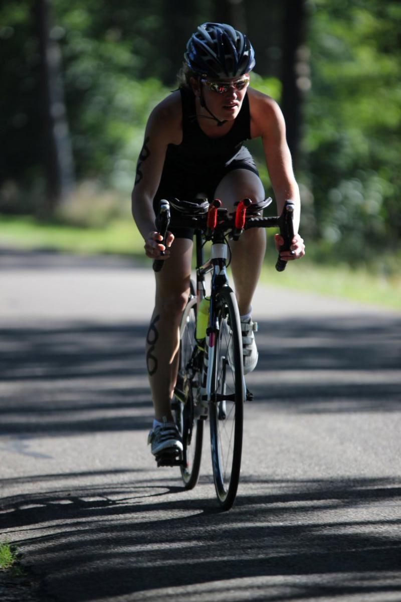 Een vrouw met een helm op fietst over de weg.