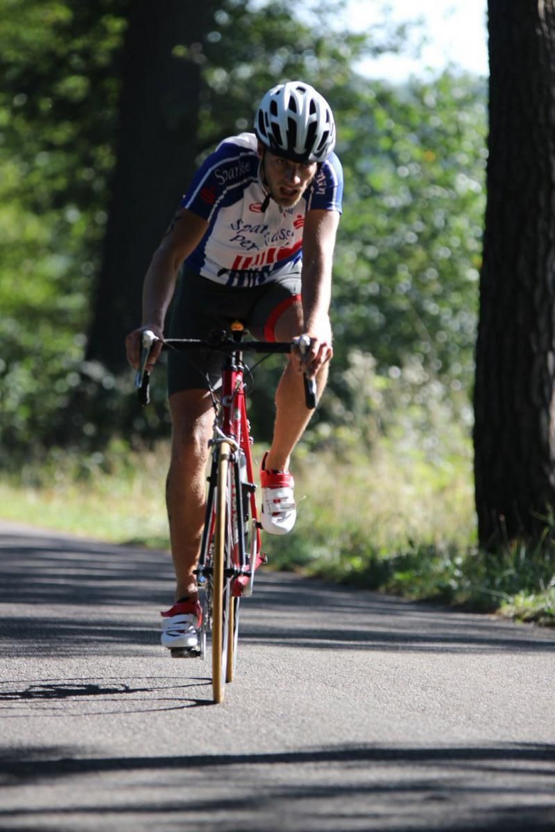 Een man met een helm rijdt op een fiets over een weg