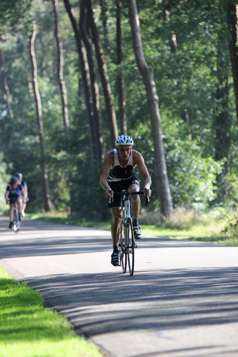 Een man fietst over een pad in het bos.
