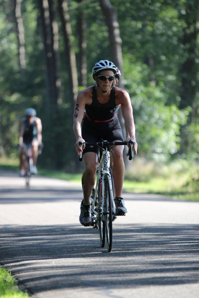 Een vrouw met een helm op fietst over de weg.