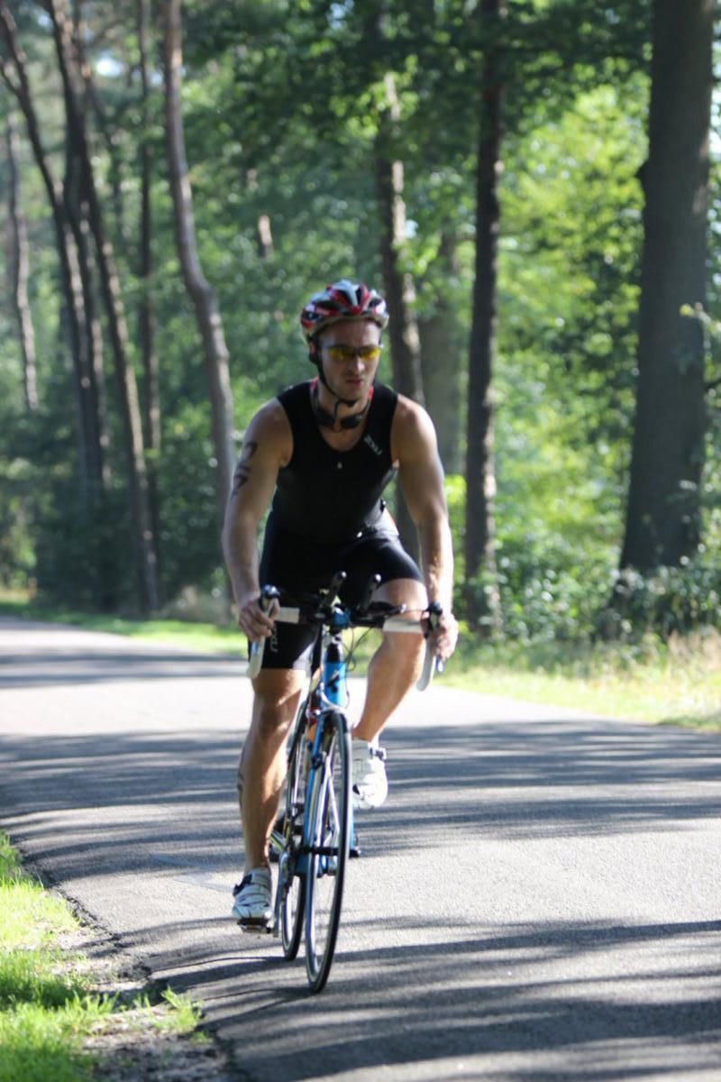 Een man fietst over een weg in het bos.