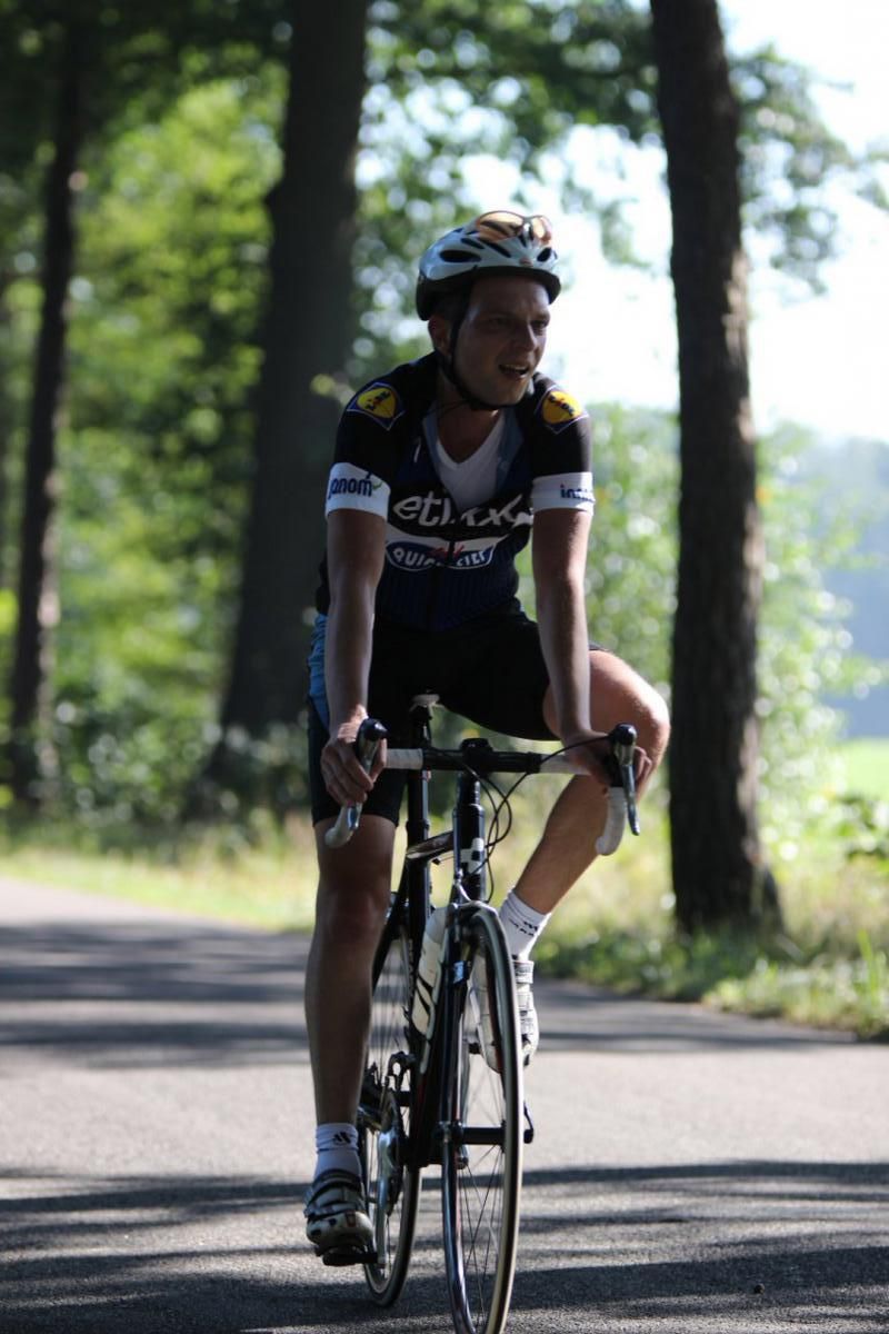 Een man met een helm rijdt op een fiets over een weg