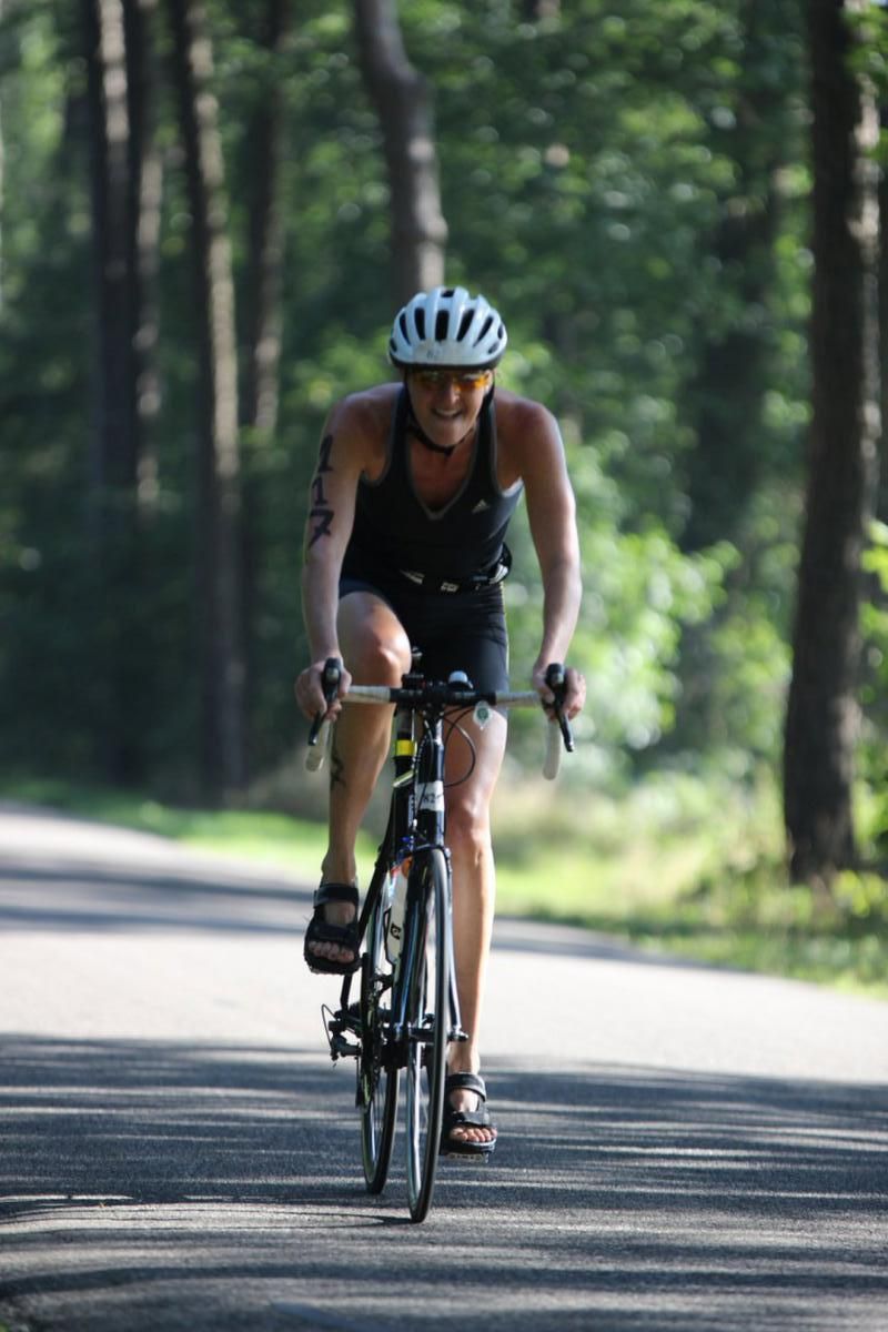 Een vrouw met een helm op fietst over de weg.