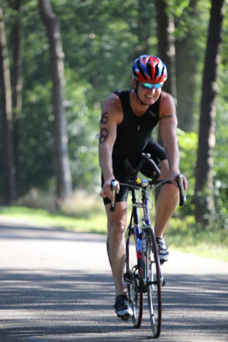 Een man met een helm rijdt op een fiets over een weg