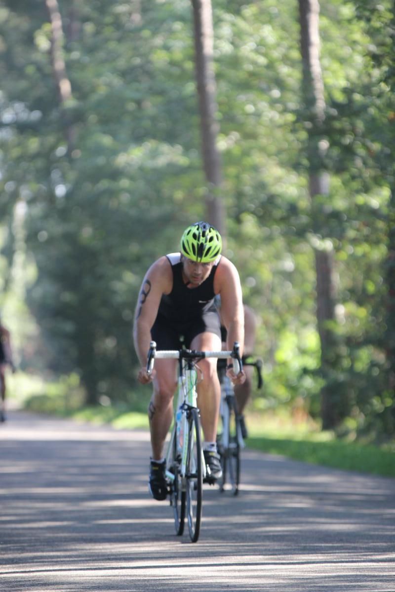 Een man met een helm rijdt op een fiets over de weg.