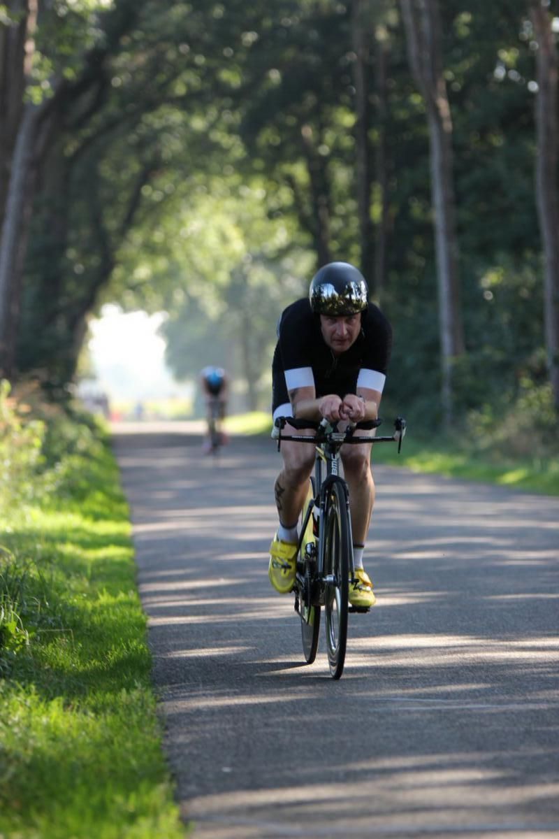 Een man met een helm rijdt op een fiets over een pad