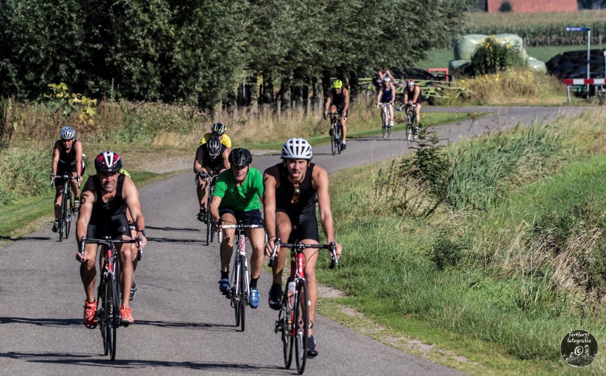 Een groep mensen fietst over een weg.