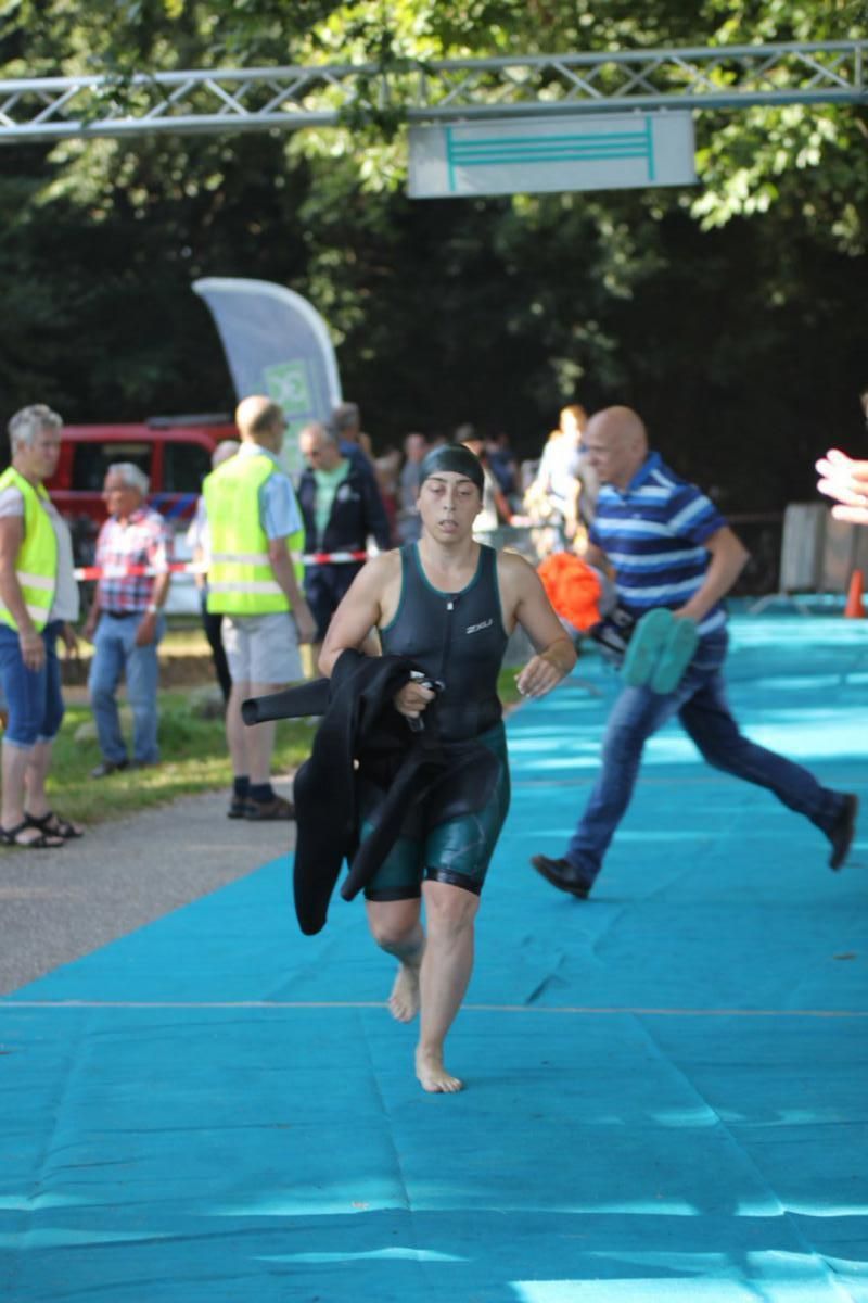 Een vrouw in een wetsuit rent op een blauwe mat