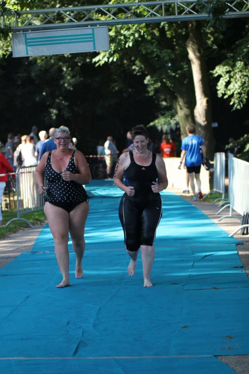Twee vrouwen in badpakken rennen op een blauwe loper