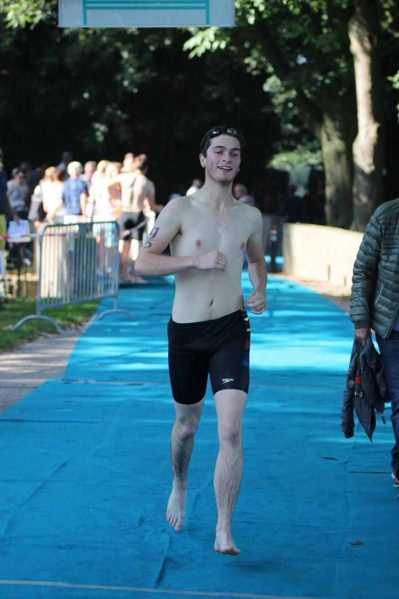 Een man zonder shirt rent op een blauwe baan.