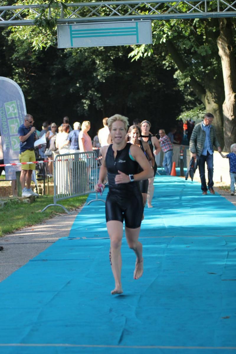Een vrouw in een wetsuit rent op een blauwe mat.