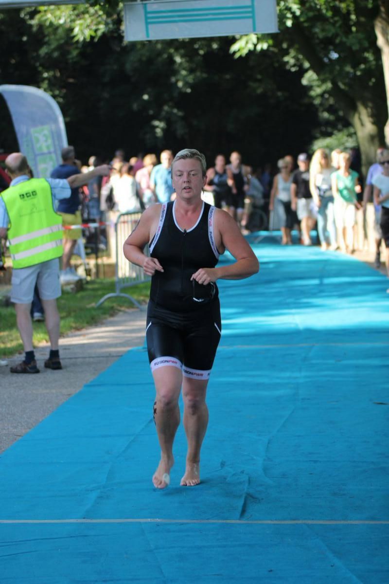Een vrouw rent op een blauwe mat voor een publiek.