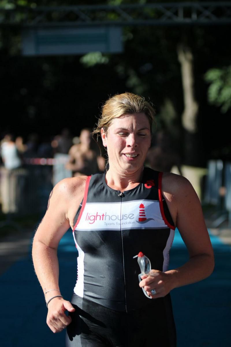 Een vrouw rent mee in een triatlon en houdt een fles water vast.