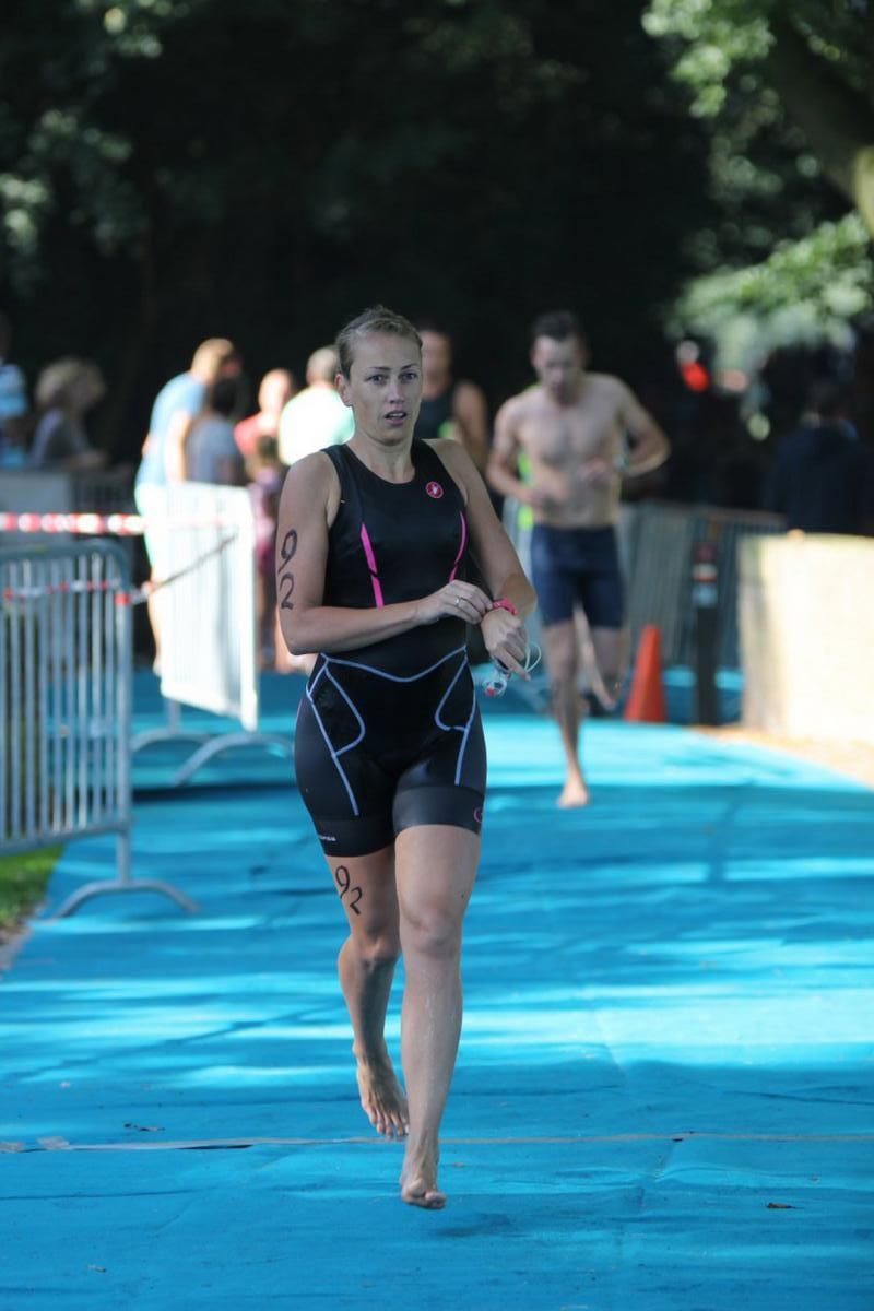 Een vrouw rent mee in een triatlon op een blauwe baan.