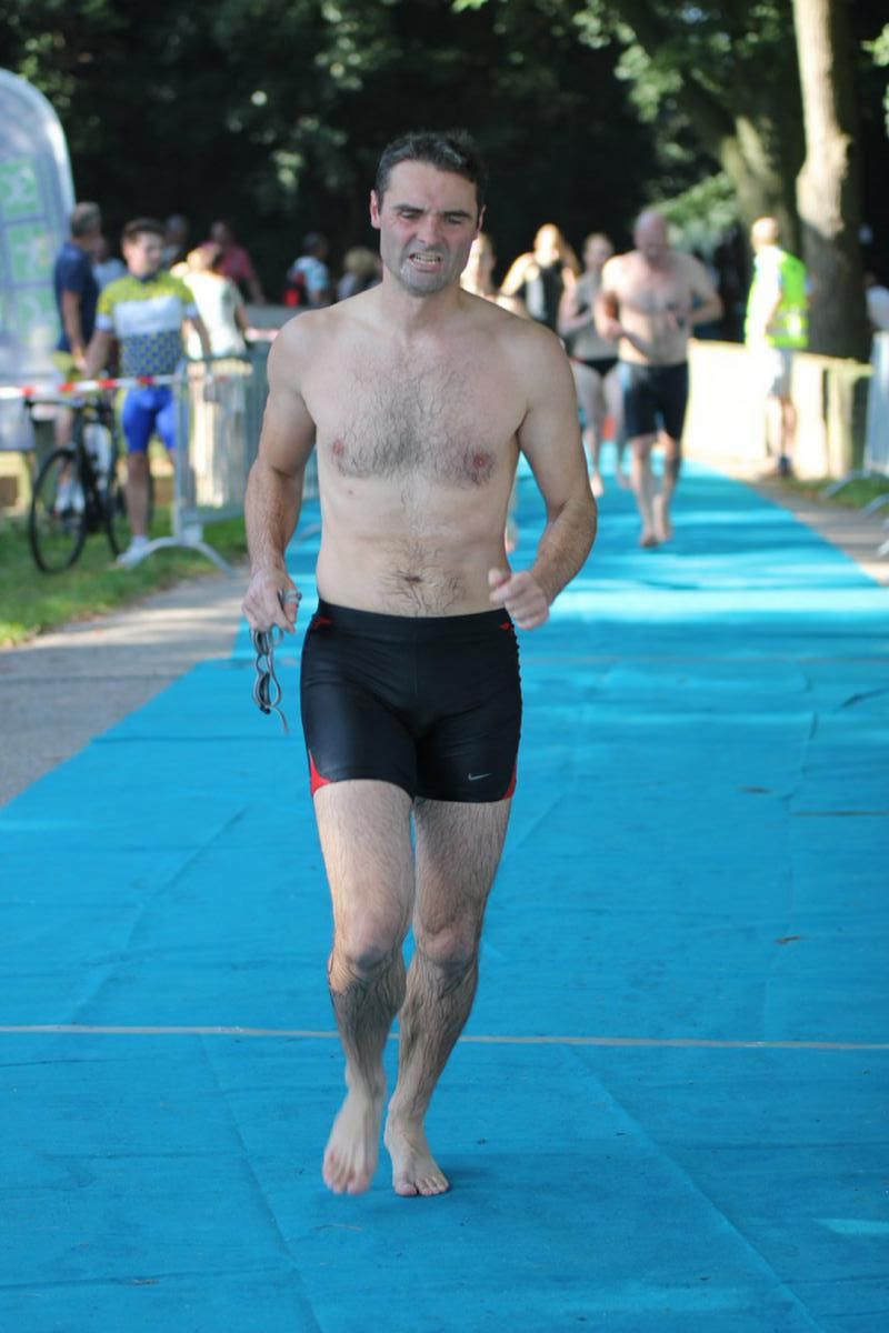 Een man zonder shirt rent over een blauwe loper