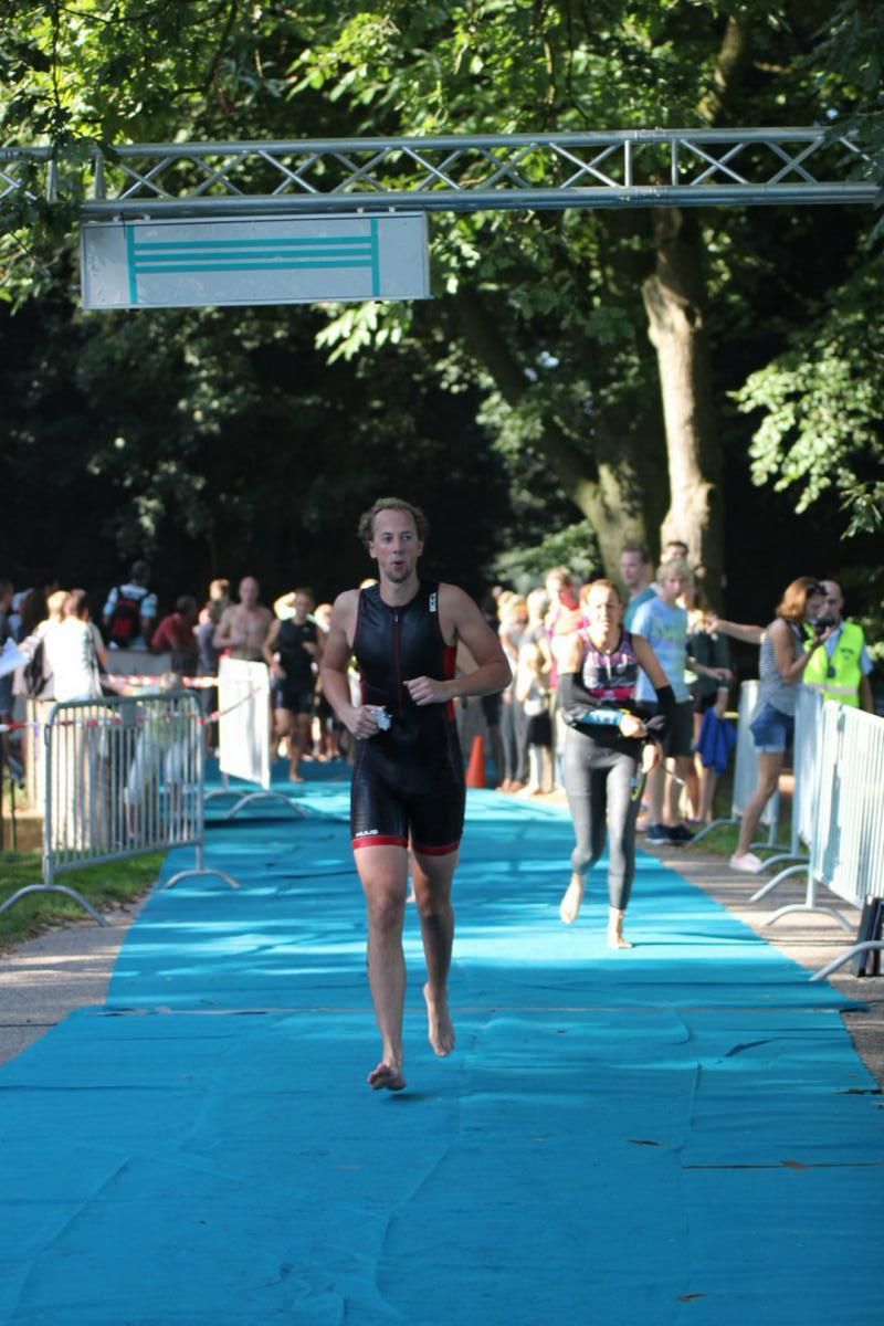 Een man rent over een blauwe loper voor een menigte.