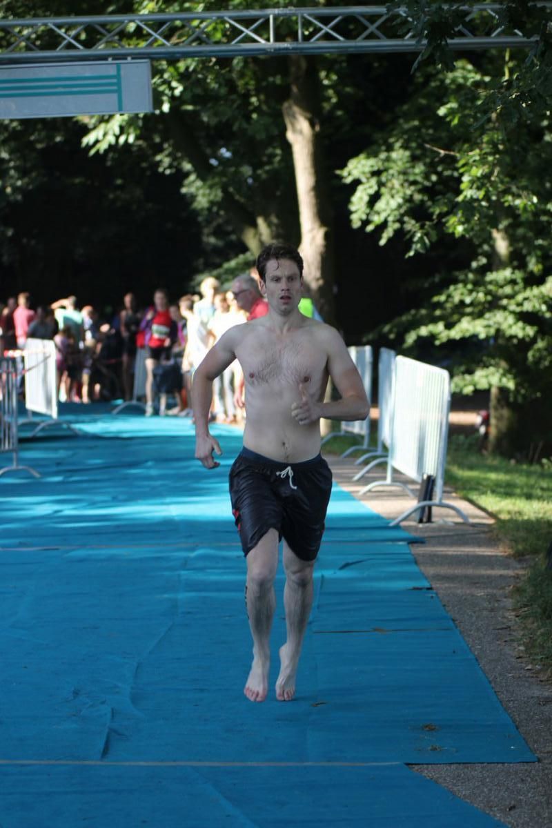 Een man zonder shirt rent over een blauwe loper.