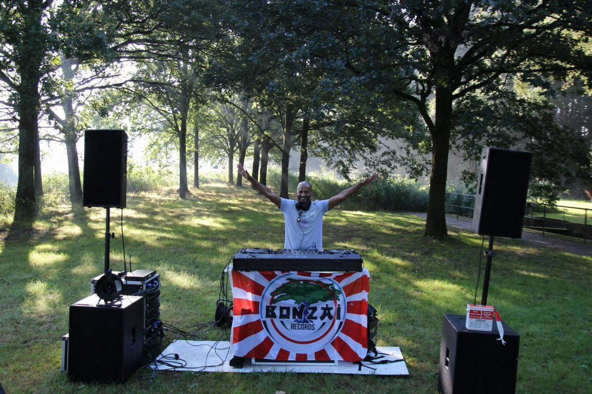 Een man staat voor een dj-booth met de tekst konza