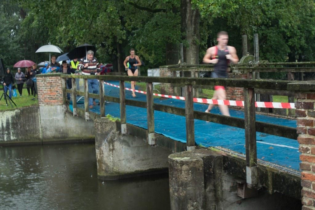 Een groep mensen rent over een brug over een watermassa.