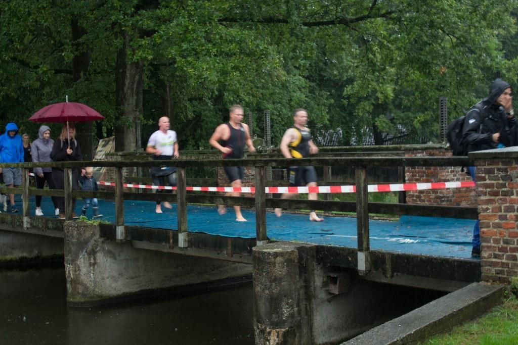 Een groep mensen rent over een brug over een rivier.