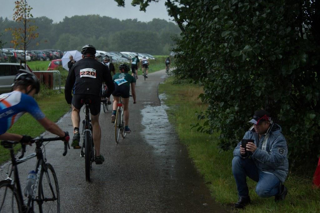 Een man die een foto maakt van een groep fietsers in de regen