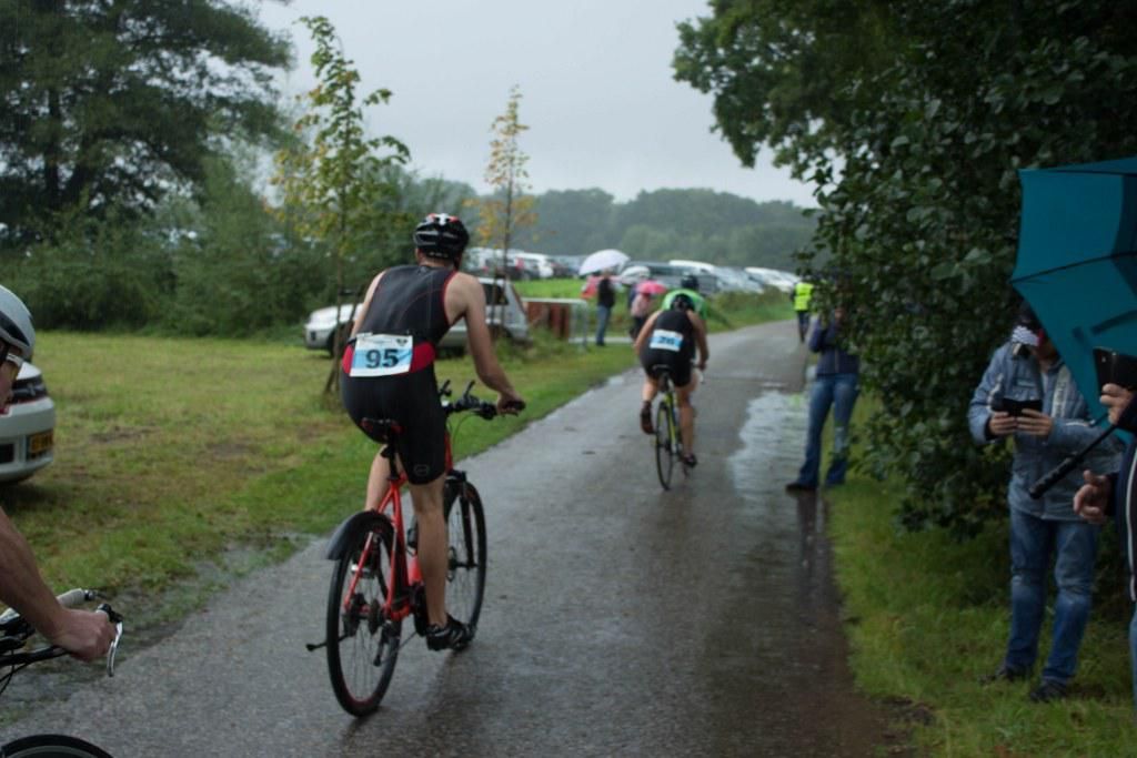 Een groep mensen fietst over een natte weg.