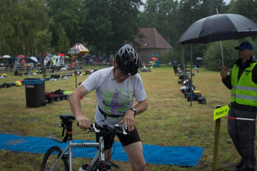 Een man staat naast een fiets in een veld.