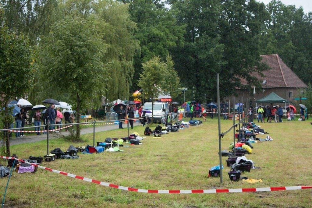 Een groep mensen is verzameld in een veld met een gebouw op de achtergrond.