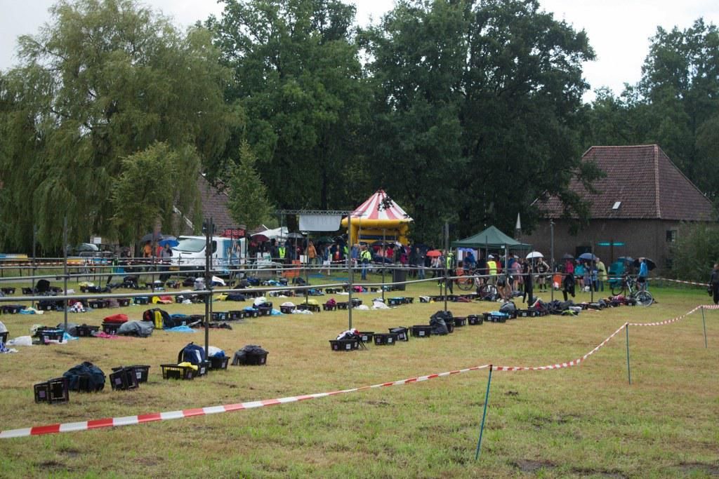 Een groep mensen is verzameld in een veld met een reuzenrad op de achtergrond