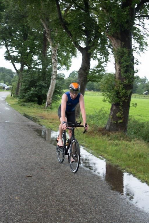 Een man fietst over een natte weg