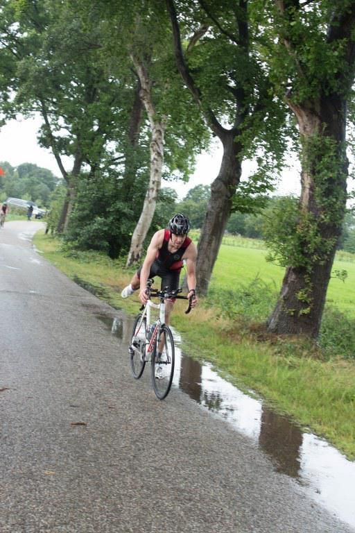 Een man fietst over een natte weg.