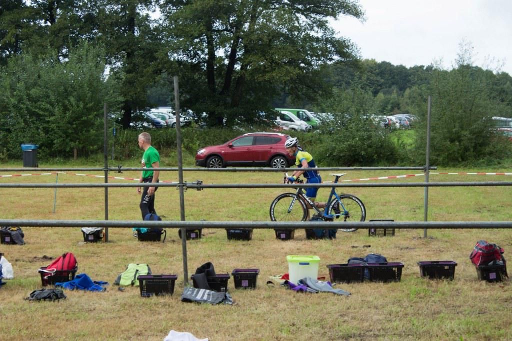Een man loopt in een veld met een fiets op de achtergrond.