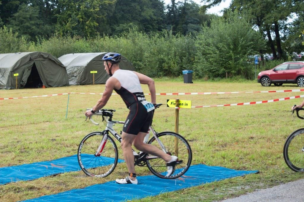 Een man fietst op een blauwe mat in een veld.