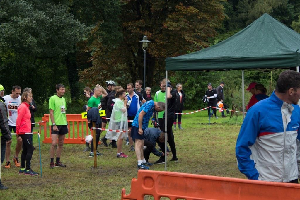 Een groep mensen staat in een veld voor een tent.