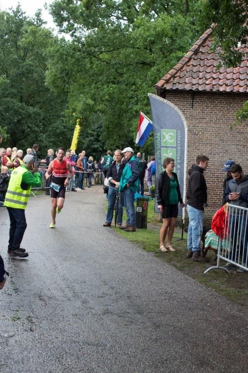 Een groep mensen staat langs de kant van de weg en kijkt naar een marathon.
