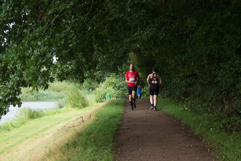 Twee mensen rennen over een pad langs een meer.