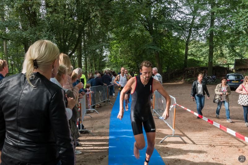 Een man rent op een blauwe loper tijdens een triatlon.