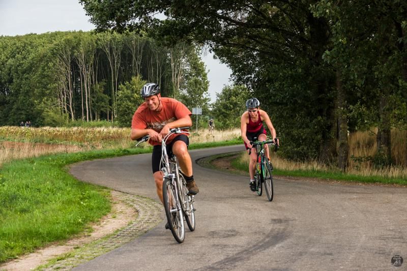Een man en een vrouw fietsen over een landweg.