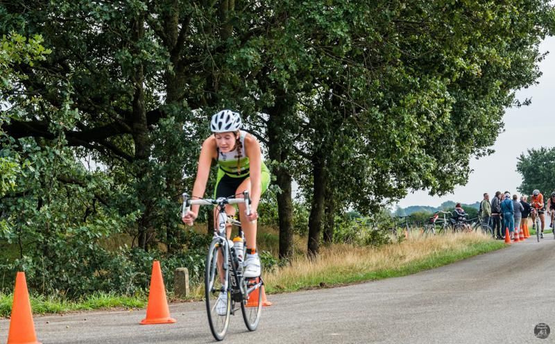 Een vrouw fietst over een weg langs kegels.