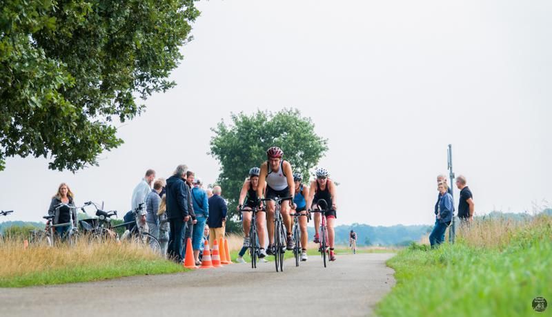 Een groep mensen fietst over een weg.