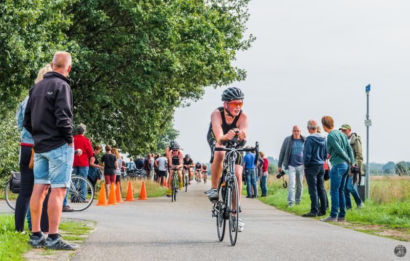 Een man fietst over een weg voor een menigte mensen.