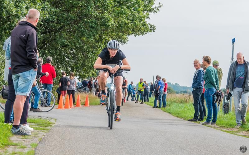 Een man fietst over een weg voor een menigte mensen.