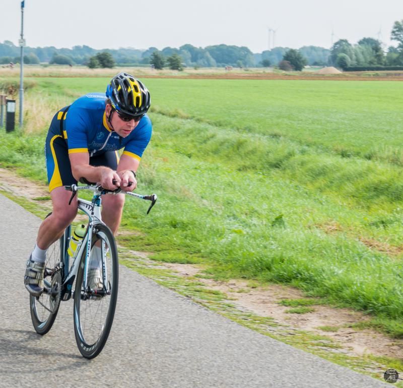 Een man met een helm rijdt op een fiets op een pad