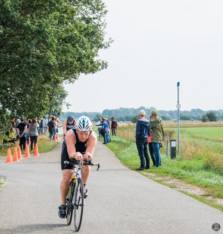 Een man met een helm rijdt op een fiets over een weg