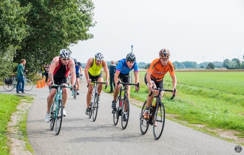 Een groep mannen fietst over een weg.