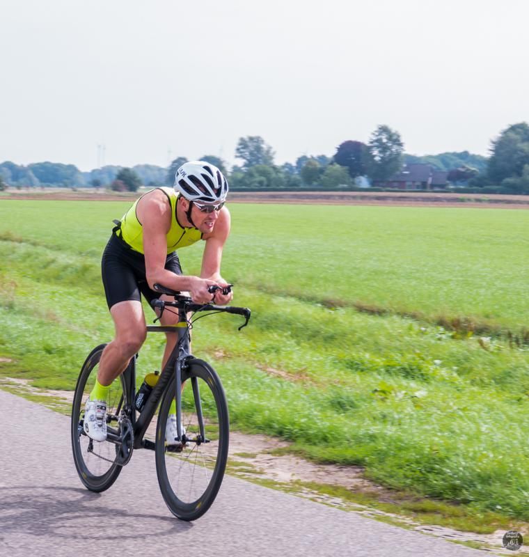 Een man met een helm rijdt op een fiets op een weg