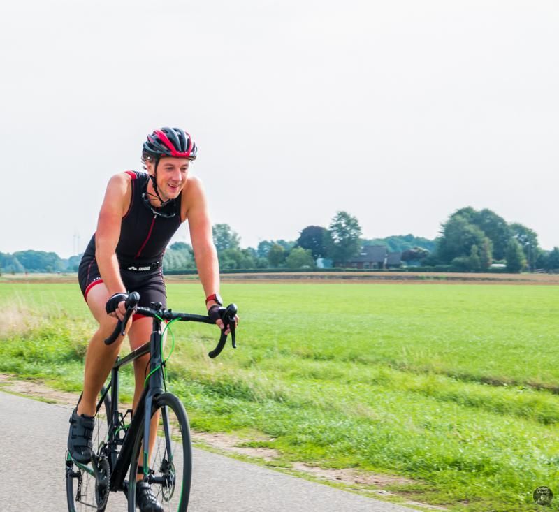 Een man met een helm rijdt op een fiets op een weg