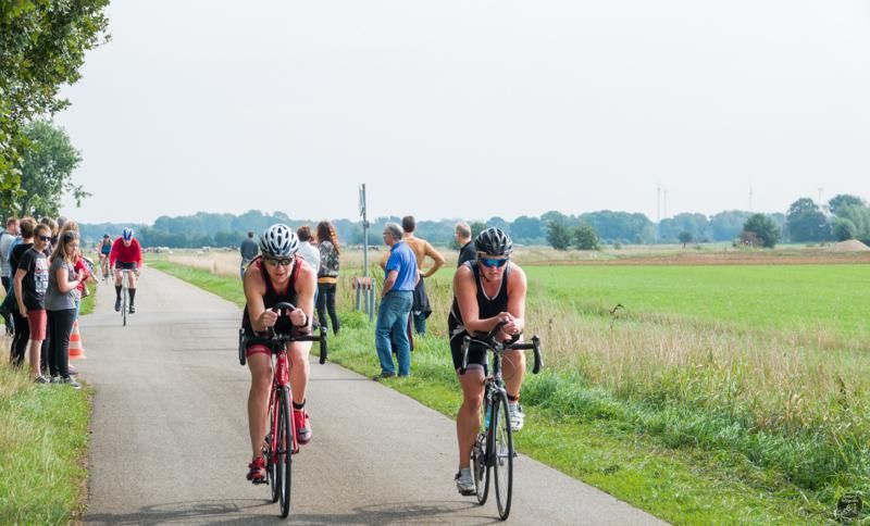 Twee mensen fietsen over een weg.